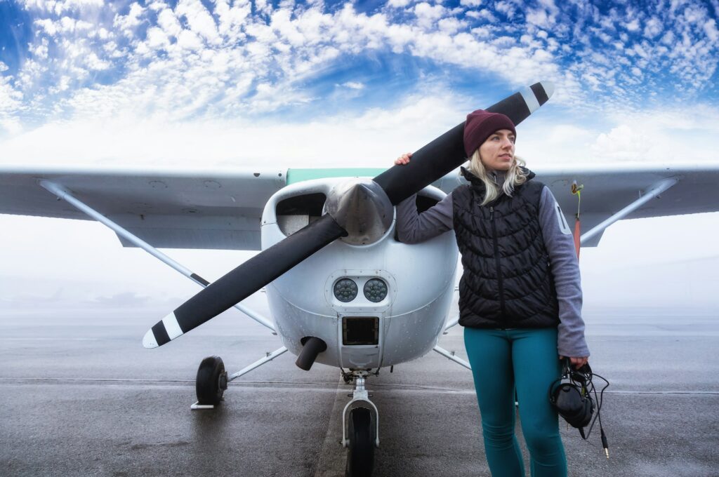 Young Caucasian Female Student Pilot is standing in front of a Single Engine Airplane